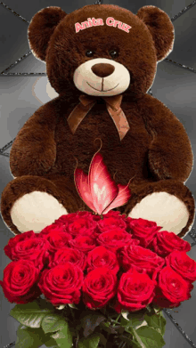 a brown teddy bear with anita cruz written on it sits next to a bouquet of red roses