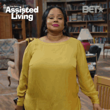 a woman in a yellow shirt is standing in a living room with the words assisted living on the bottom