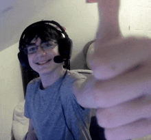 a young man wearing headphones and giving a thumbs up