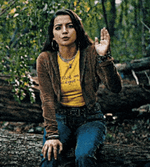 a woman is sitting on a log wearing a yellow shirt that says " i love you " on it