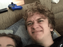 a man with curly hair is making a funny face while laying on a couch