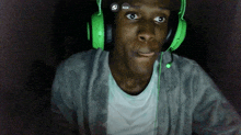 a man wearing green headphones is looking at the camera with a qrx icon above his head