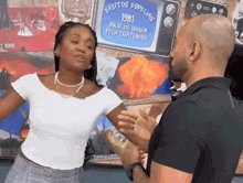 a man and a woman are standing next to each other in front of a wall with pictures on it .