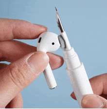 a person is holding a pair of ear buds with a brush attached