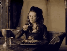 a woman is sitting at a table with a plate of food and a knife .