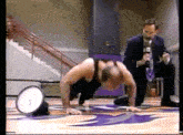 a man is doing push ups on a basketball court while another man watches