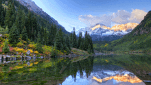 a lake surrounded by mountains and trees with a mountain reflected in the water