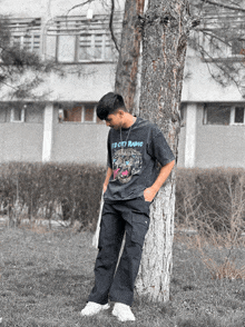 a young man leaning against a tree wearing a t-shirt that says ff city radio