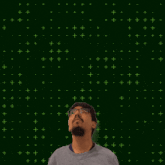 a man with glasses and a beard stands in front of a green background with 9 + 8 written on it