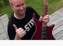 a man wearing a black shirt that says g-str is holding a guitar