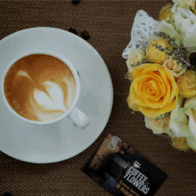 a cup of coffee on a saucer next to a coffee flowers advertisement