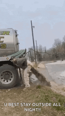 a man is standing next to a truck that is pumping water out of a hole in the ground .