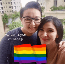 two women are posing for a picture with a rainbow flag in the foreground and the caption calon lgbt cilacap