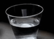 a glass of water is sitting on top of a table .