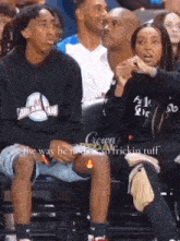 a man and a woman are sitting in the stands at a basketball game and the man is talking to the woman .