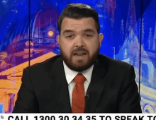 a man in a suit and tie is standing in front of a sign that says " call 1300 30 34 35 to speak to "