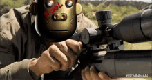 a man holding a sniper rifle with a robot face on his head with the word fool written on it