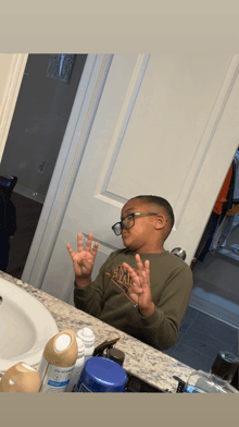 a young boy wearing glasses is looking at himself in a mirror