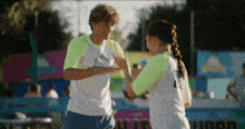 a boy and a girl are high fiving each other in front of a sign that says ' i love you ' on it