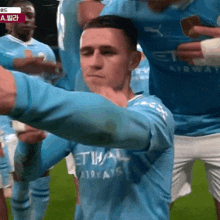 a man in a blue etihad airways jersey stands on a soccer field