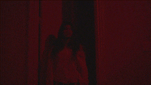 a woman in a white shirt is standing in a hallway