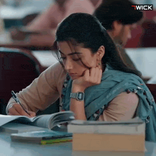a woman sits at a desk with a watch on her wrist that says ' wick ' on it