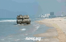 a military tank is driving on a sandy beach .