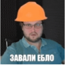 a man wearing a blue shirt and an orange hard hat with russian writing on it .