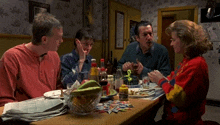 a family sits at a table with plates of food and bottles on it