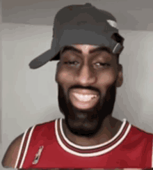 a man wearing a hat and a red chicago bulls jersey smiles