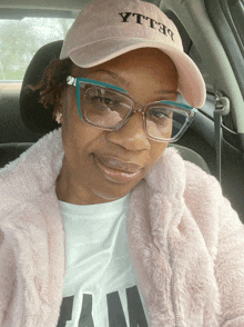 a woman wearing glasses and a pink hat that says yttho