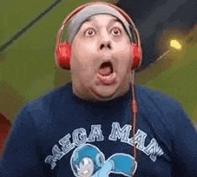 a man wearing headphones and a mega man t-shirt is making a funny face .