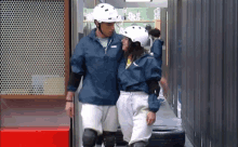 a man and a woman wearing white helmets are walking down a hallway together