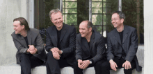 a group of men in suits are sitting on a ledge smiling