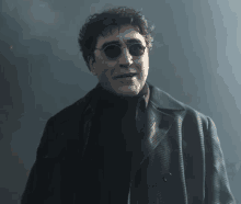 a man wearing sunglasses and a black coat is standing in a dark room