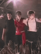 three people are dancing in front of a crowd at a concert .