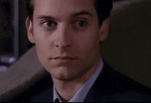 a close up of a man 's face with his eyes closed in a suit and tie .