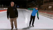 a man and a girl are ice skating on a rink and the man is wearing a jacket with the letter x on it