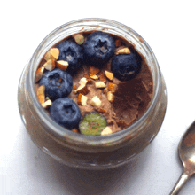 a jar of chocolate pudding with blueberries and pistachios