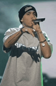 a man is singing into a microphone while wearing a beanie and a shirt that says off