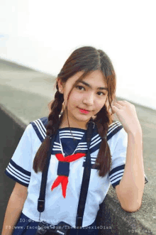 a young girl in a sailor uniform with braids and suspenders