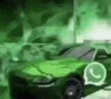 a green car is driving down a street with a whatsapp logo on the side .