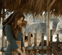 a woman in a blue dress is standing under a thatched roof with the words venda de primeira geratura below her