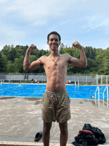 a shirtless man is flexing his muscles in front of a pool