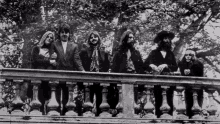 a black and white photo of a group of people on a railing