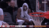 a basketball player with a towel around his head sits in front of a basketball net