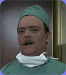 a man with a mustache is wearing a green surgical gown and a surgical cap .