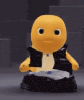 a yellow stuffed animal wearing a black vest is sitting on top of a black box .