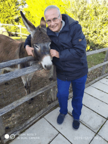 a man petting a donkey with a redmi note 7 ai dual camera behind him