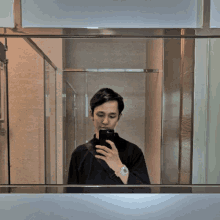 a man is taking a selfie in a bathroom mirror